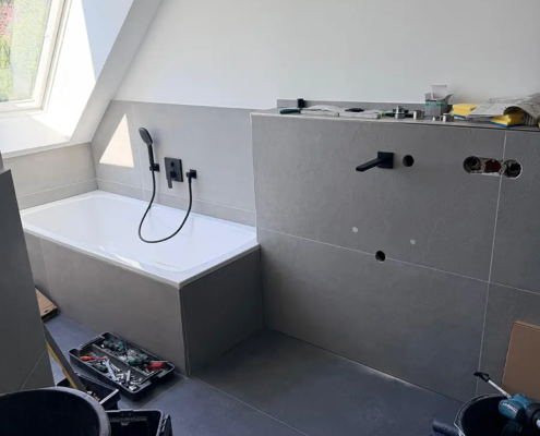 Neues Bad mit Badewanne unter der Dachschräge und großformatigen Fliesen