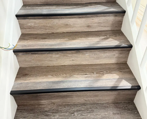 Neue Treppenstufen in Holzoptik mit schwarzen Kantenprofilen